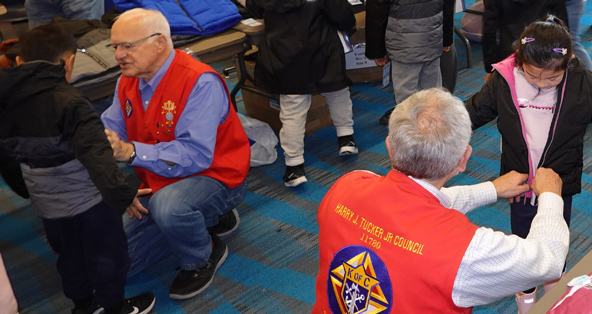 Members of KOFC11780 assist children in trying on new coats